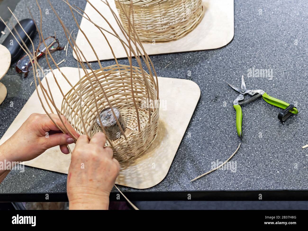 Il maestro tessera un canestro di ramoscelli salici. Foto Stock