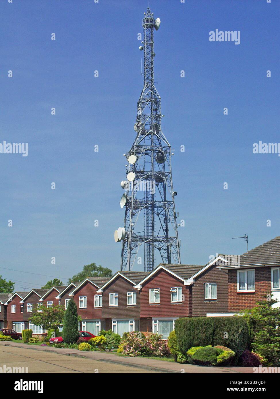 Strada con fila di stesso stile casa indipendente e giardino anteriore sotto alto cella di comunicazione torre palo telecomunicazioni satellite piatto Brentwood UK Foto Stock
