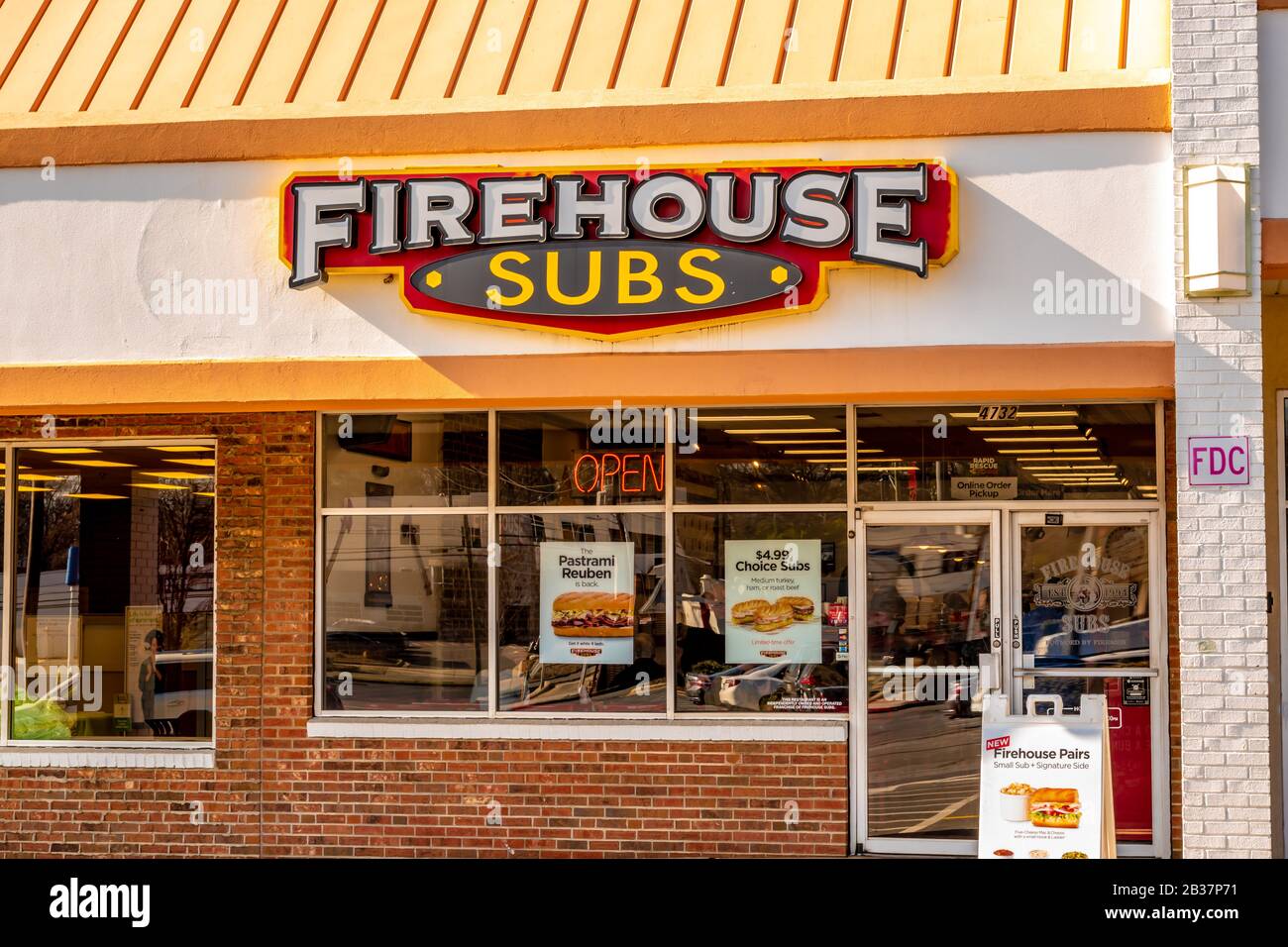 Primo piano orizzontale di media grandezza del negozio di sandwich fast food 'Firehouse Subs' che mostra il marchio e il logo sulla facciata dell'edificio sopra le finestre e l'entrata. Foto Stock