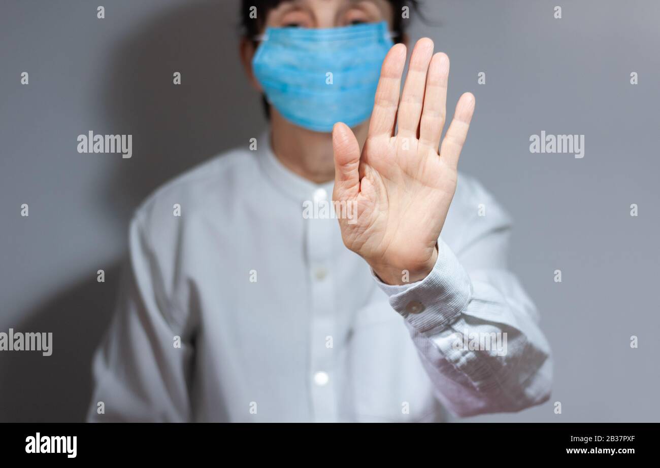 Arrestare la quarantena del coronavirus e il concetto di inquinamento atmosferico pm2.5. Donna anziana malata che indossa maschera respiratore per proteggere con braccio allungato. Wuhan, Cina ep Foto Stock