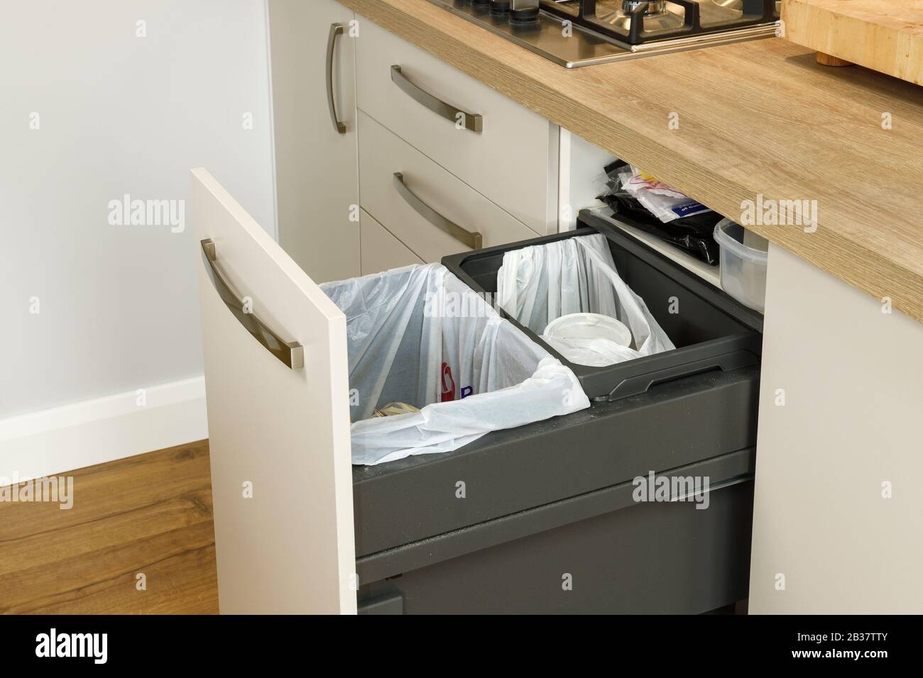 Estrarre i contenitori di riciclaggio in una cucina moderna Foto Stock