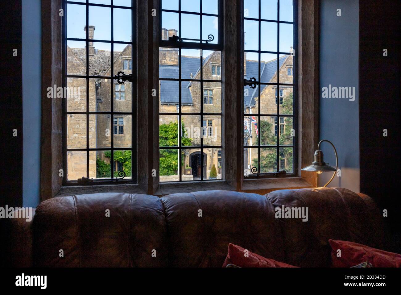 The Lygon Arms Hotel (Circ. 1300) visto attraverso la finestra al piano superiore del Broadway Deli, Broadway, Worcestershire, Inghilterra, Regno Unito Foto Stock