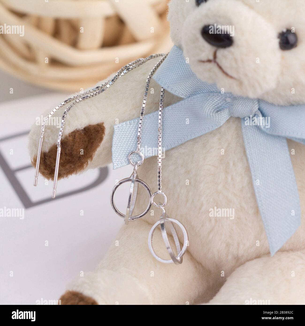 Un paio di splendidi orecchini in argento sterling 925 si presentano su un orso giocattolo Foto Stock