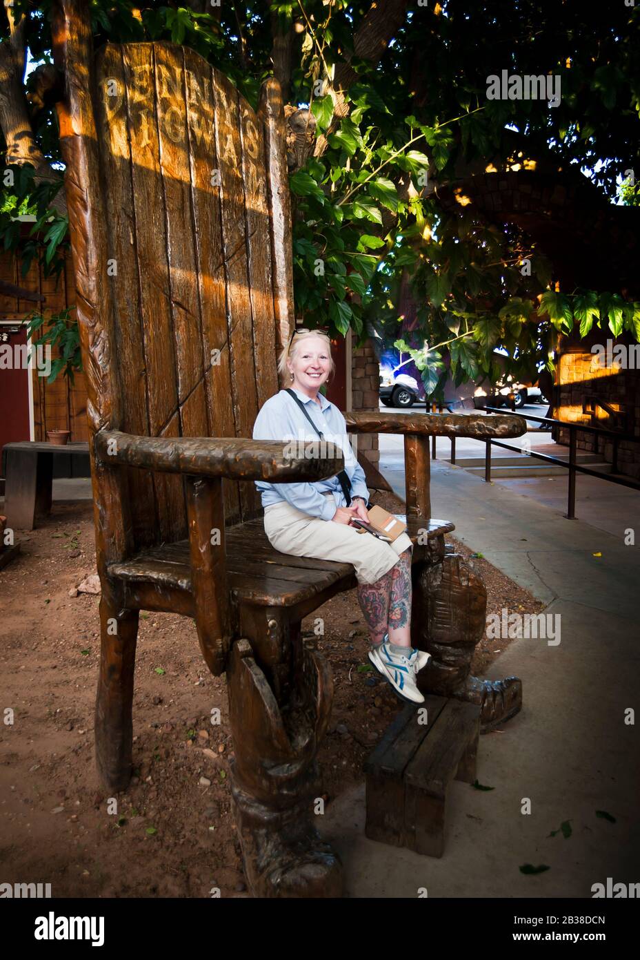 donna seduta da sola su una grande sedia di legno scuro, Foto Stock