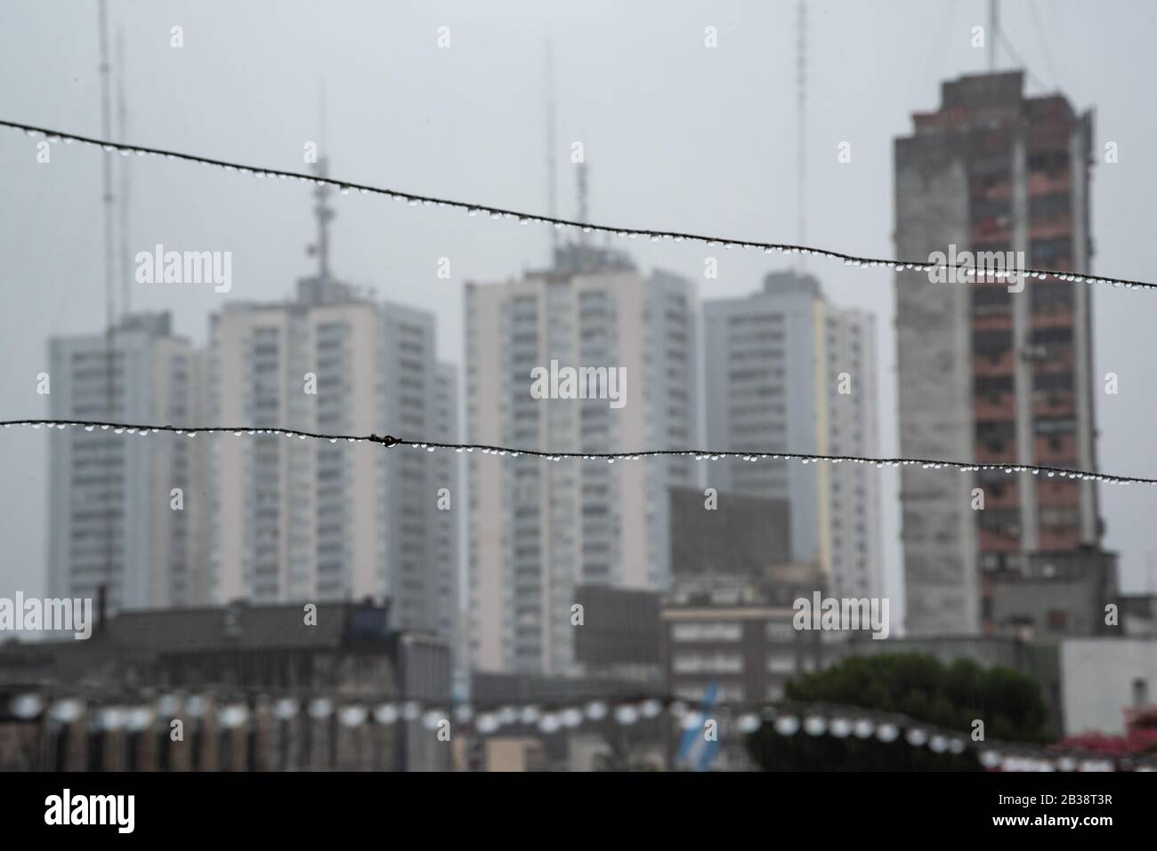Cavo Clothesline pieno di piccole gocce in una giornata di pioggia con un fuoco selettivo su di loro e profondità di campo molto poco profonda con uno sfondo sfocato Foto Stock