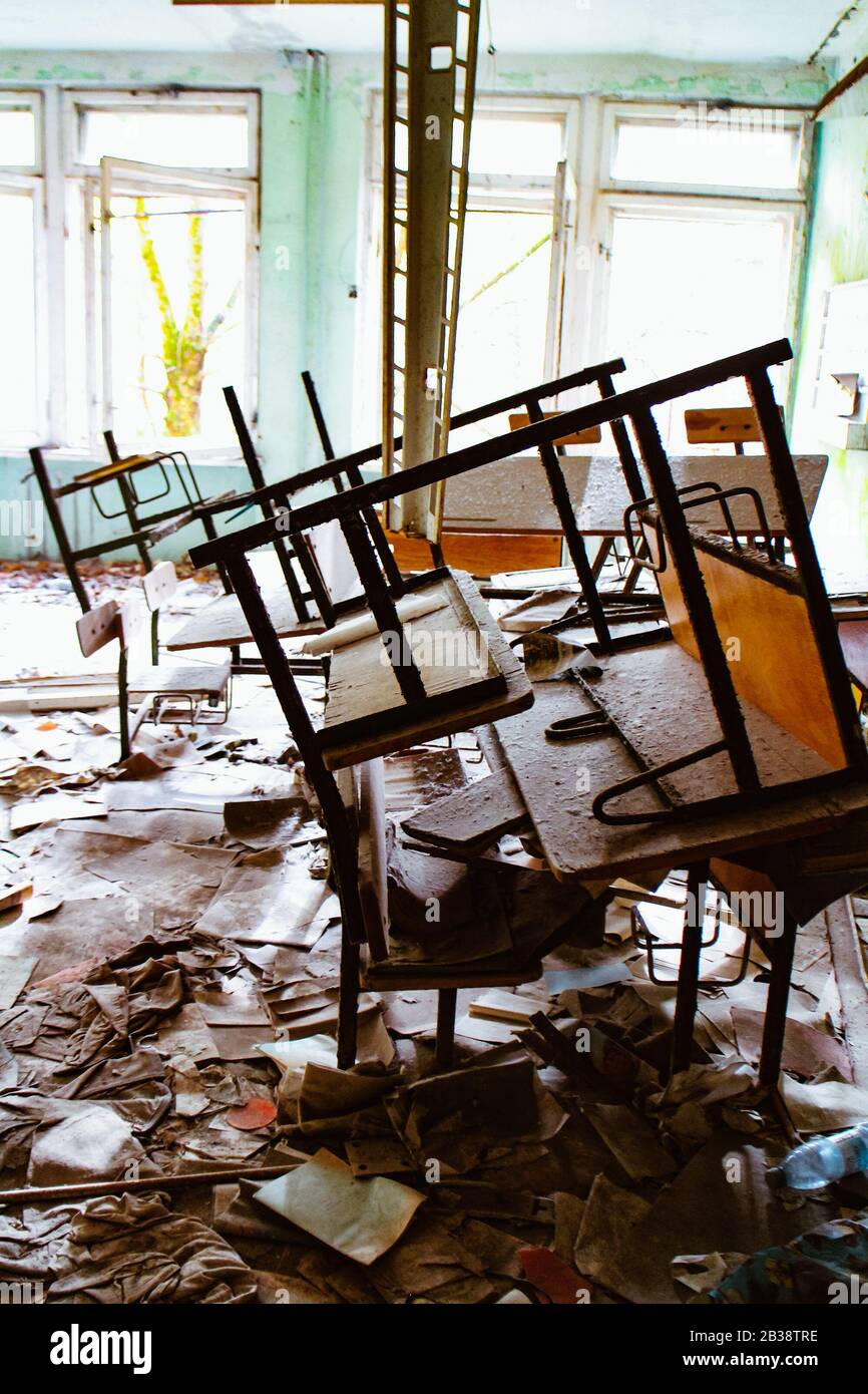 Scena caotica con banchi impilati in una sala scuola della scuola elementare abbandonata numero 3 a Pripyat, Ucraina, zona di esclusione di Chernobyl. Foto Stock