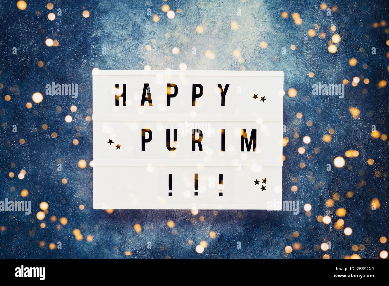 Concetto di celebrazione Purim. Happy Purim scritto in scatola di luce su sfondo blu. Vista dall'alto, copia spazio. Vista dall'alto Foto Stock