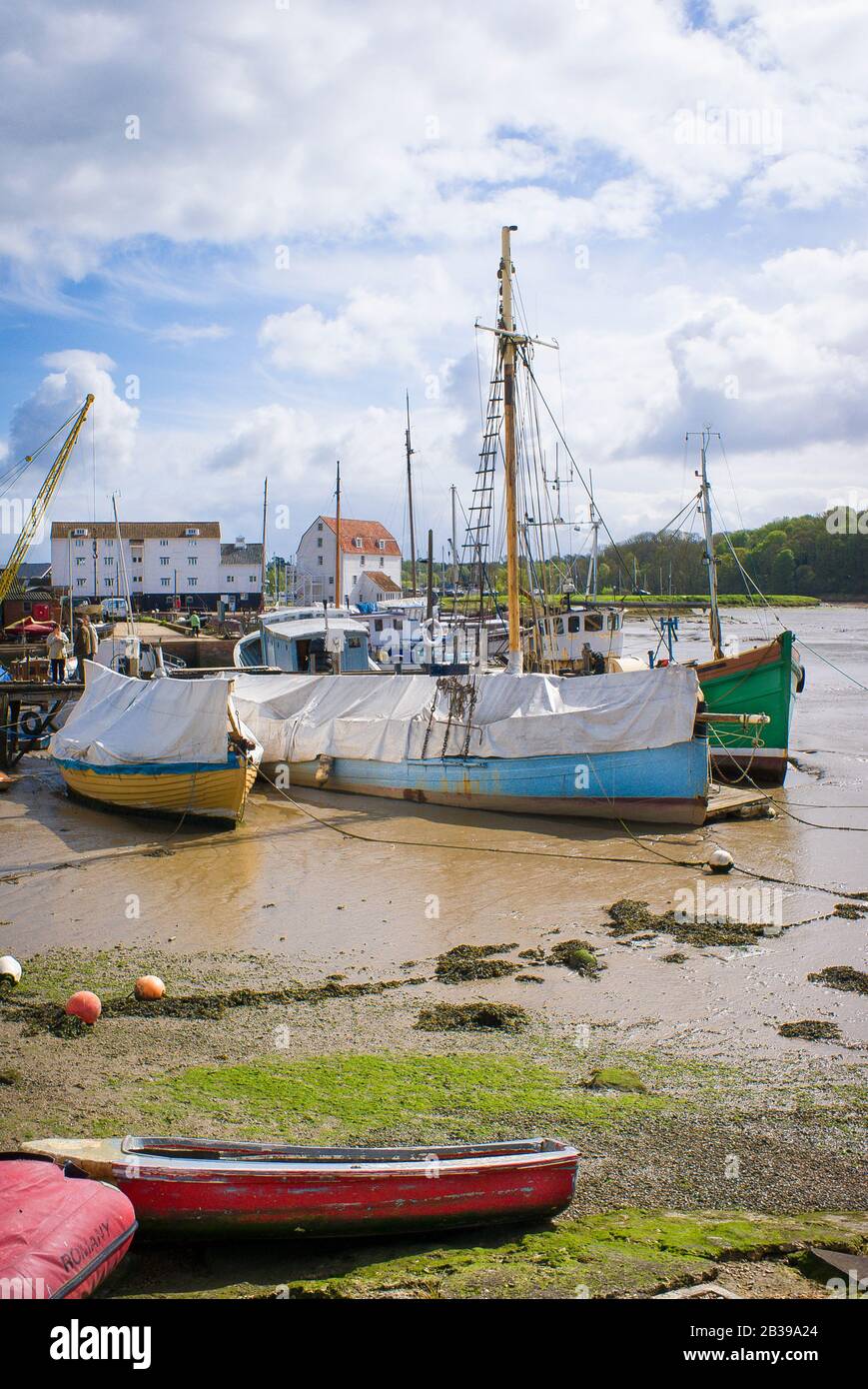 La bassa marea lascia piccole barche bloccate nel porto di Woodbridge sul fiume Deben nel Suffolk Inghilterra UK Foto Stock