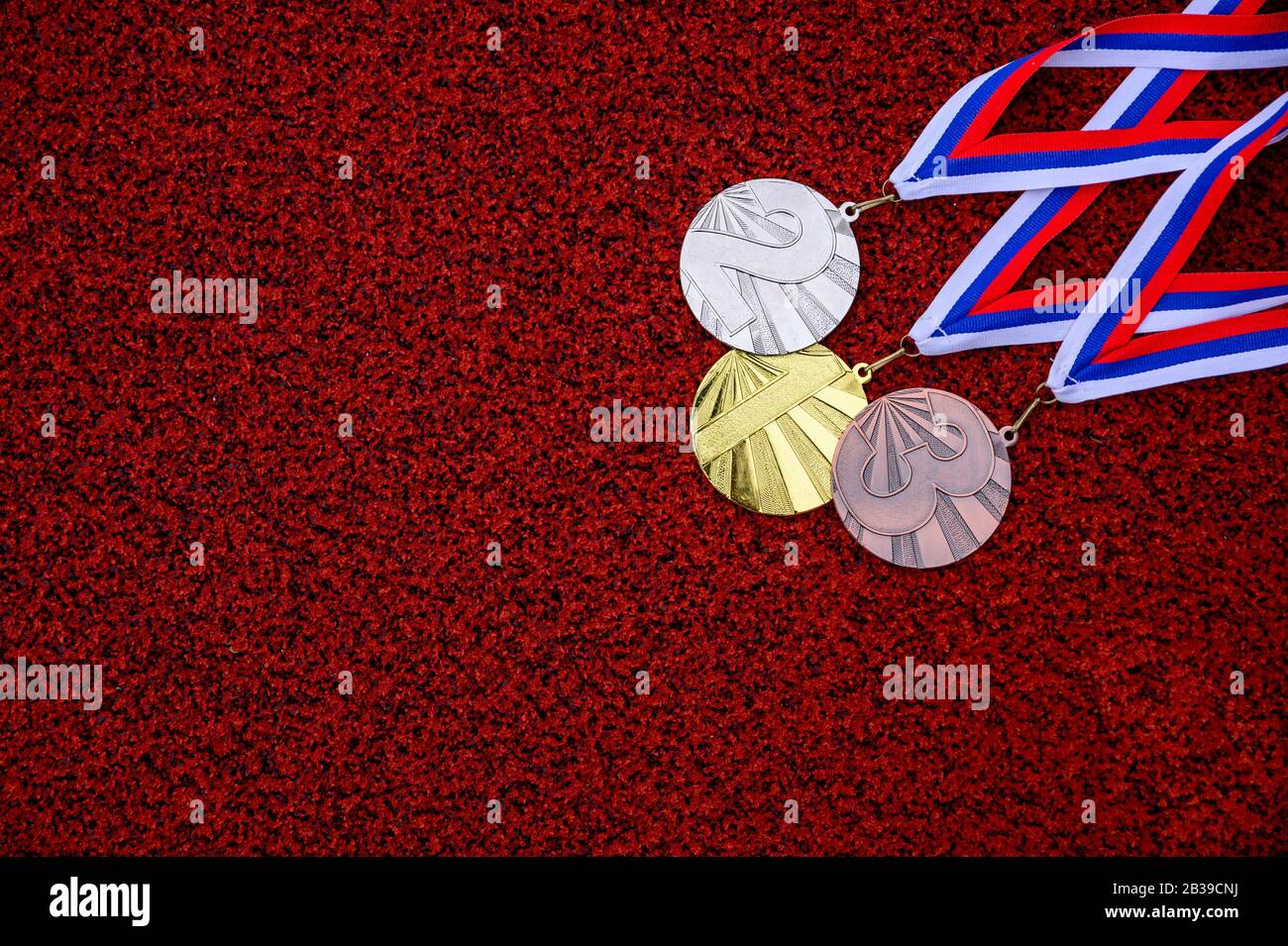 Medaglia fissata alla pista di atletica rossa, medaglia d'oro e bronzo, carta da parati rossa, medaglia concetto di cerimonia Foto Stock