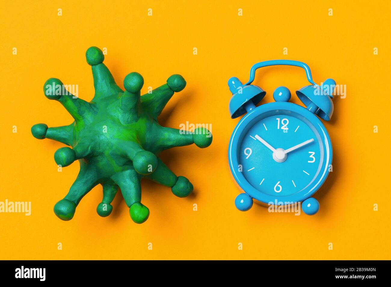 Layout del coronavirus e sveglia su sfondo giallo, vista dall'alto. Concetto del periodo di incubazione COVID-19 Foto Stock