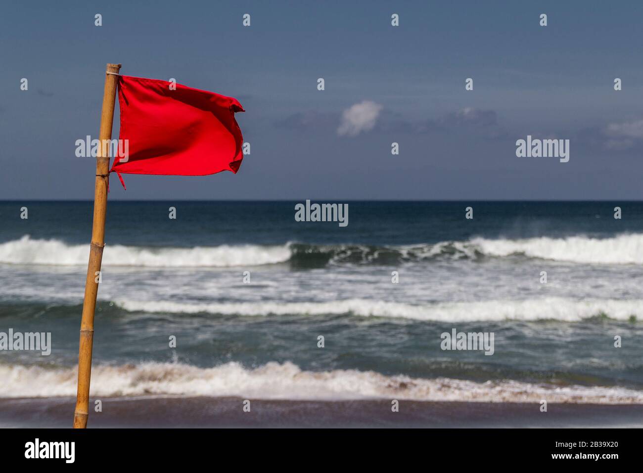 Bandiera rossa che batte il vento sulla spiaggia in caso di tempesta. Foto Stock