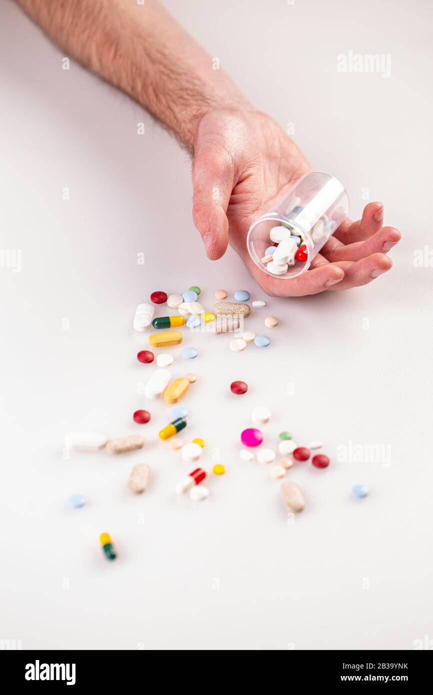 Pillole multicolore in mano d'uomo Foto Stock