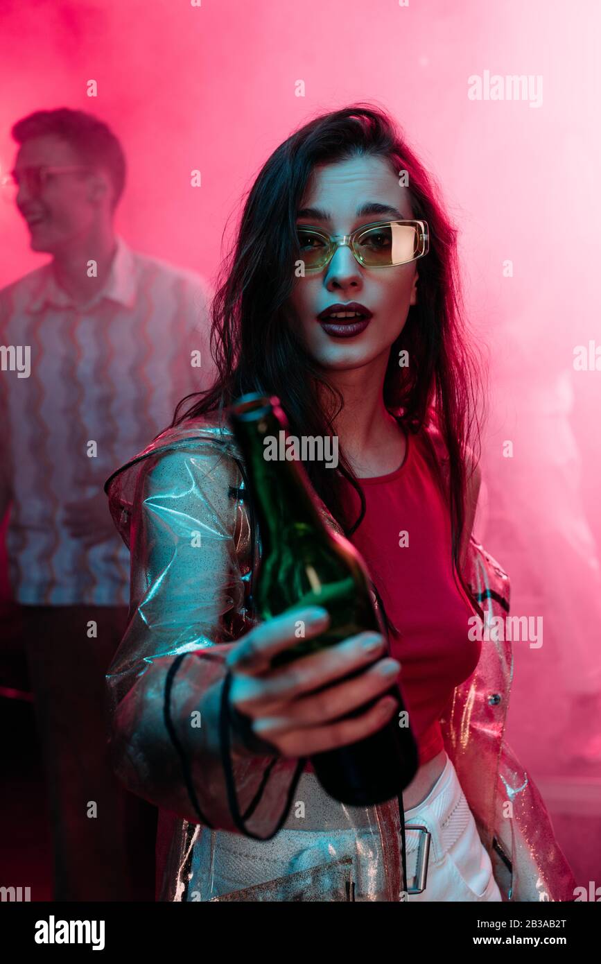 ragazza in occhiali da sole con bottiglia di alcol durante la rave in  discoteca Foto stock - Alamy