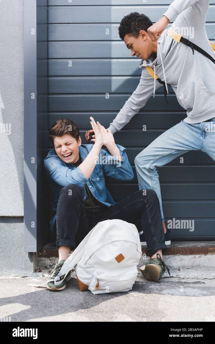 ragazzo americano africano in felpa con cappuccio e jeans che pugni il ragazzo spaventato Foto Stock