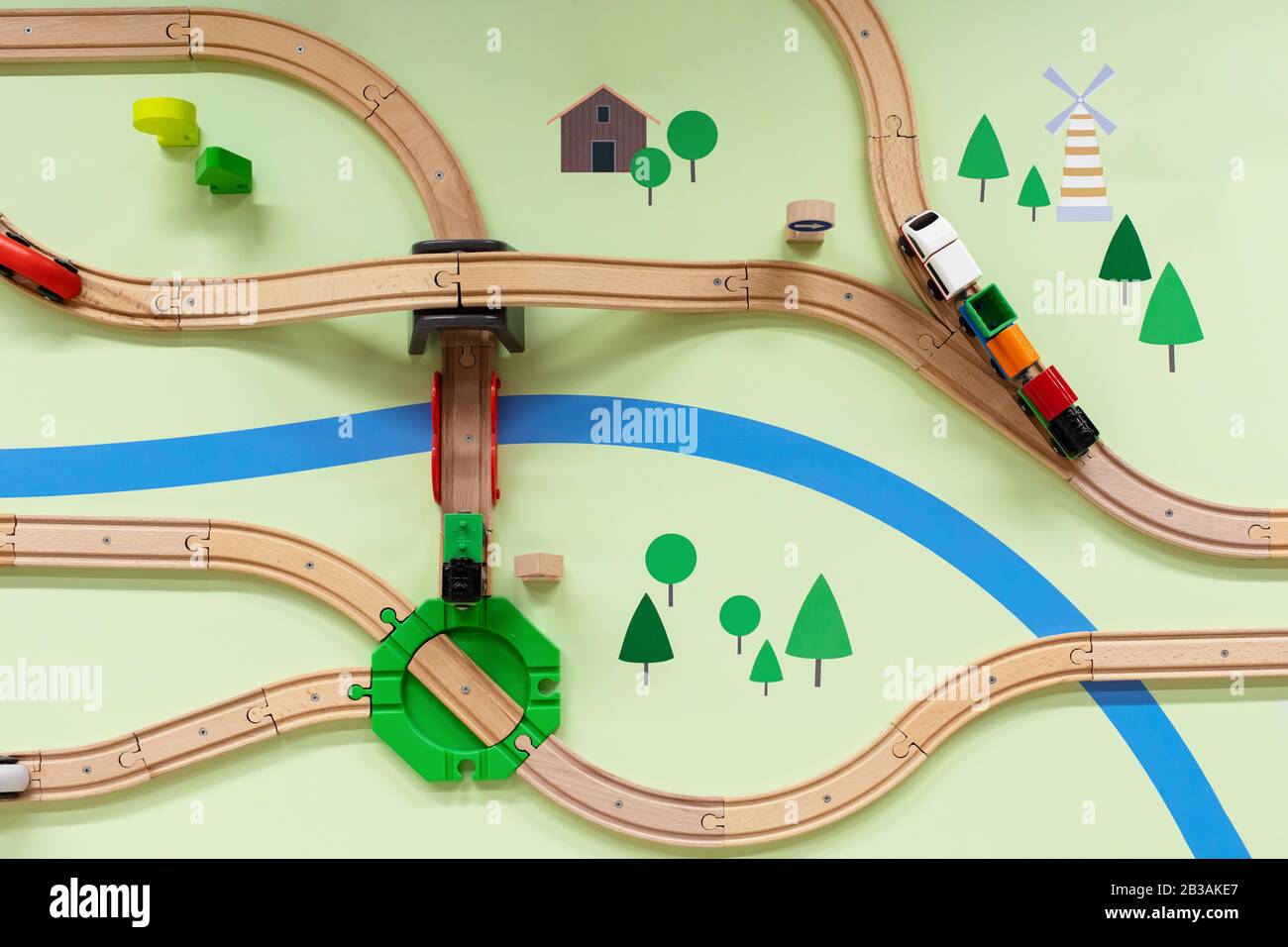 Ferrovia in legno per bambini con locomotiva a vapore, vista dall'alto. Un paesaggio dipinto con un fiume, una ferrovia giocattolo con un incrocio, un ponte e una strada jun Foto Stock
