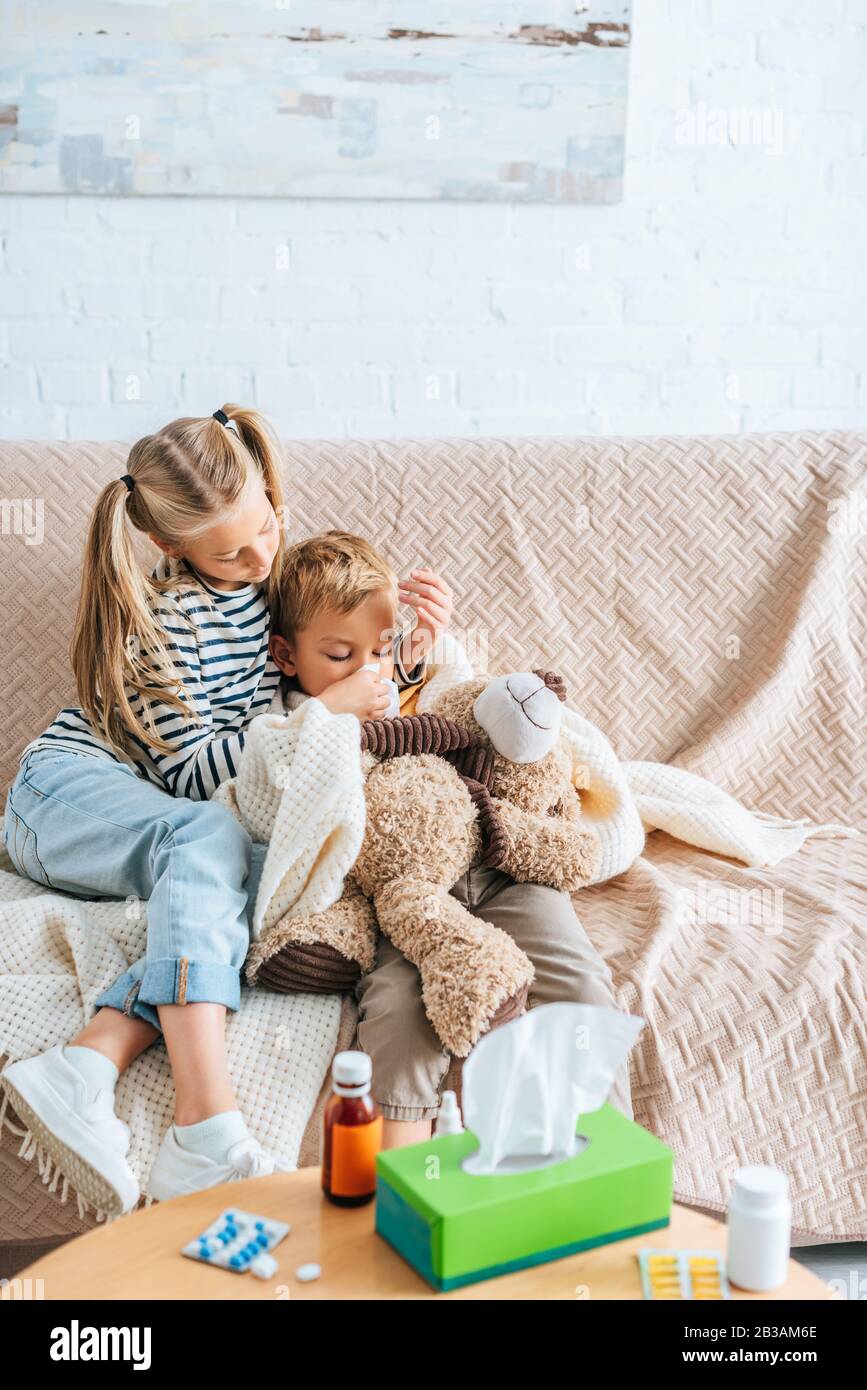 sorella attenta che puliva il naso di fratello malato con tovagliolo Foto Stock