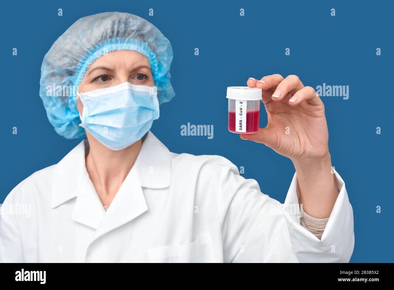 Donna di mezza età che contiene un contenitore con un esame del sangue e un vaccino contro il coronavirus Foto Stock