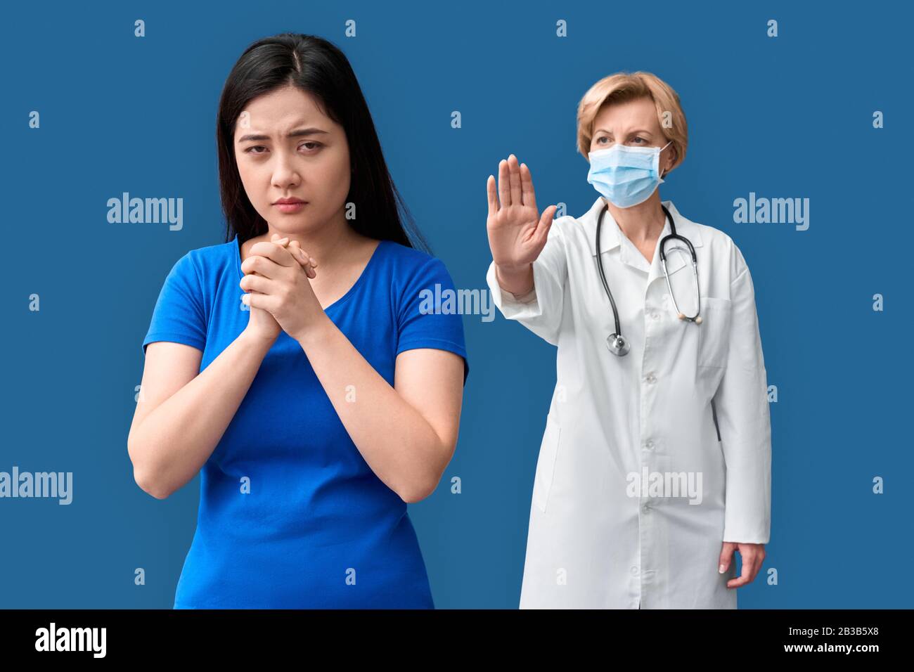Donna asiatica malata e giovane adulta che si trova di fronte al medico di mezza età Foto Stock