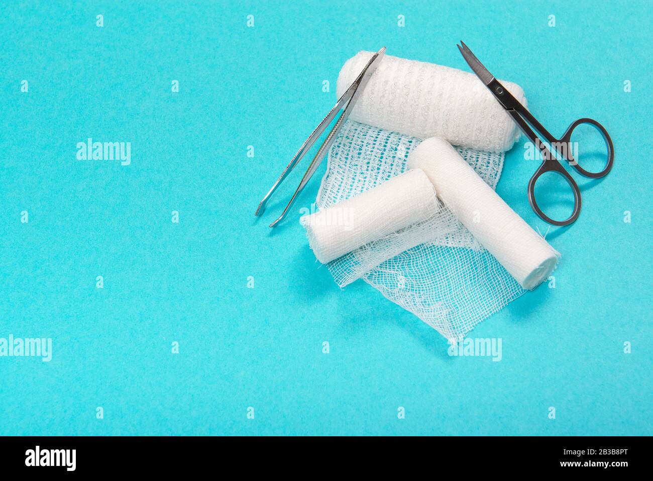 Bendaggi medici bianchi rotoli con forbici e pinzette in un kit di farmacia su sfondo blu con spazio per la copia Foto Stock