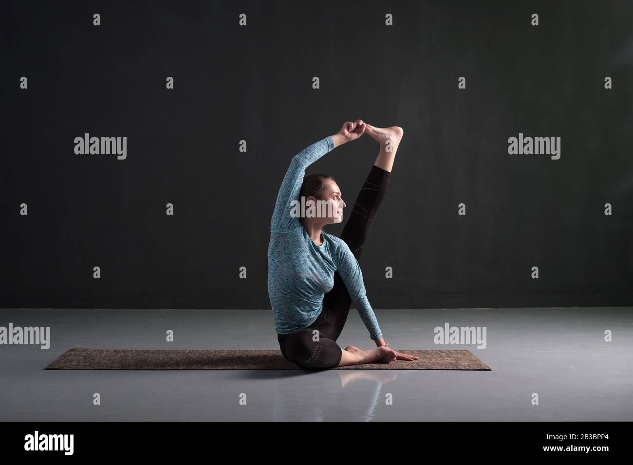 Allenamento yoga ragazza sportiva, seduto in posa Heron, Krounchasana. Aumentare la forza e la flessibilità nelle articolazioni e nei muscoli delle gambe. Studio Foto Stock