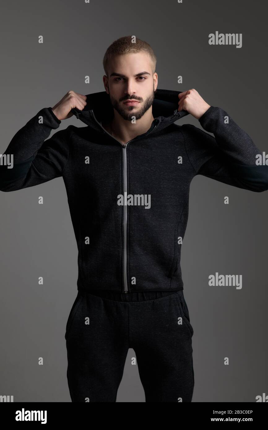 uomo biondo casual che indossa tuta in piedi e fissa la sua cappa seria su  sfondo grigio studio Foto stock - Alamy