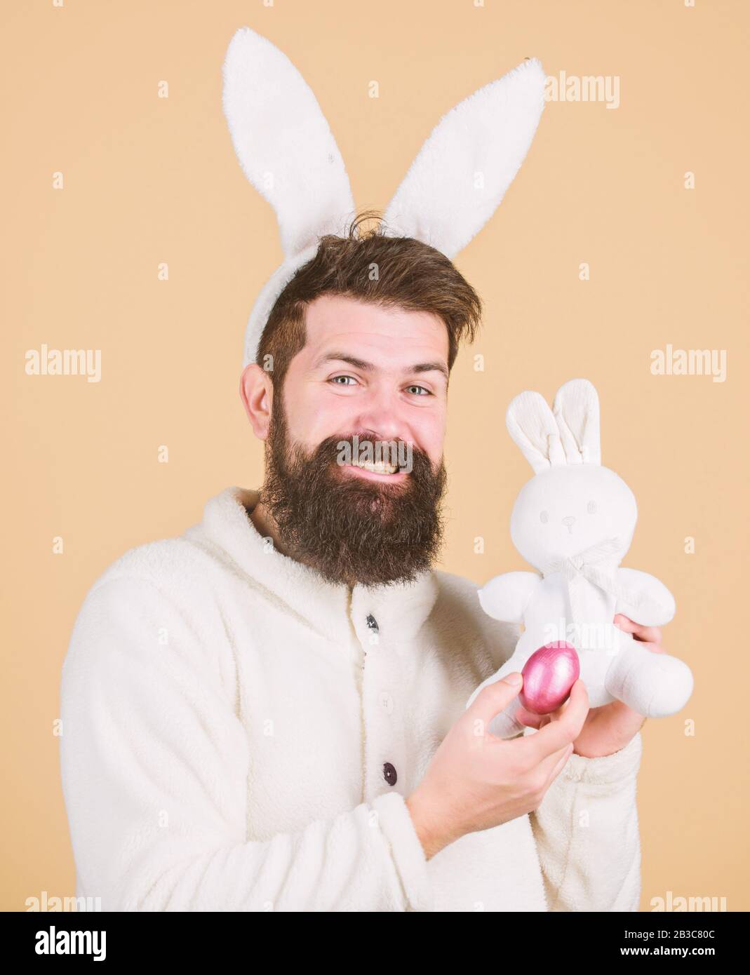 Funny bunny man orecchie morbide. L'uomo che indossa il vestito di coniglio  gioca con il giocattolo. Concetto di attività pasquali. Ancora infantile.  Festeggiate La Pasqua. Ragazzo bunny hippster allegro con lunghe orecchie