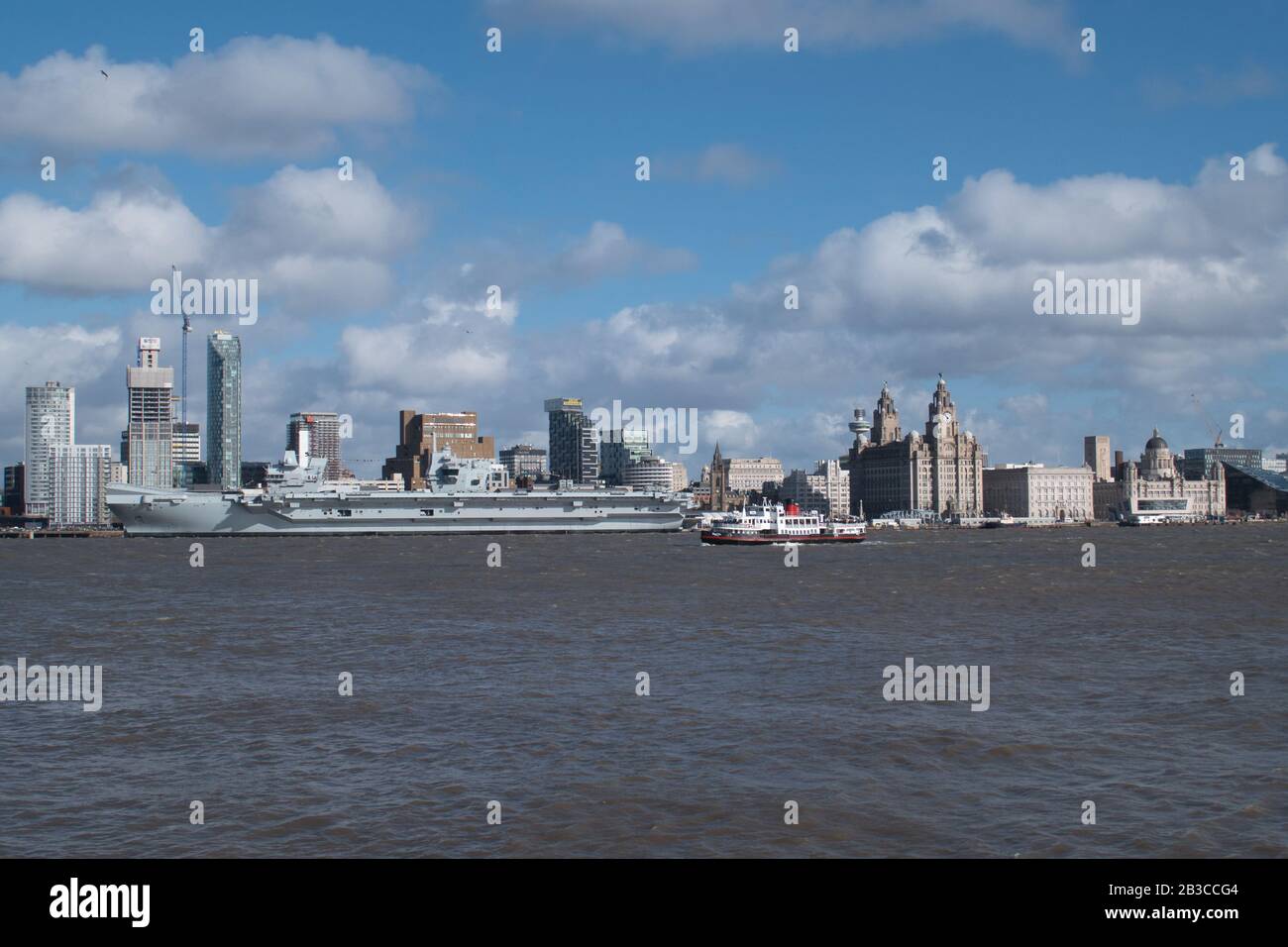 Il Mersey Ferry Royal Iris passa davanti alla compagnia aerea Prince of Wales della Royal Navy, ormeggiata presso il lungomare storico di Liverpool, patrimonio dell'umanità dell'UNESCO, sul Th Foto Stock