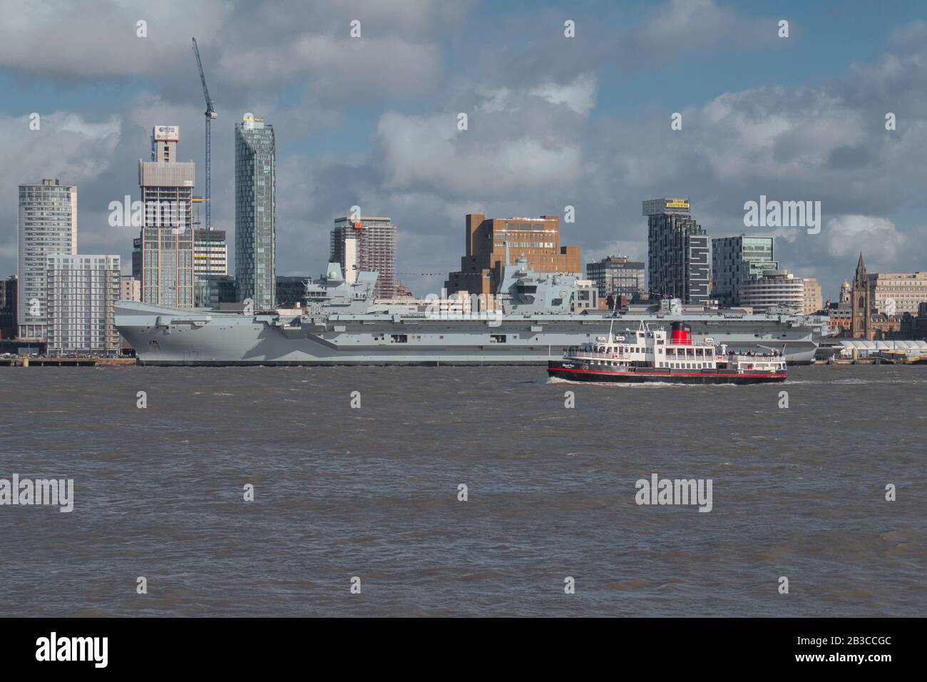 Il Mersey Ferry Royal Iris passa davanti alla compagnia aerea Prince of Wales della Royal Navy, ormeggiata presso il lungomare storico di Liverpool, patrimonio dell'umanità dell'UNESCO, sul Th Foto Stock