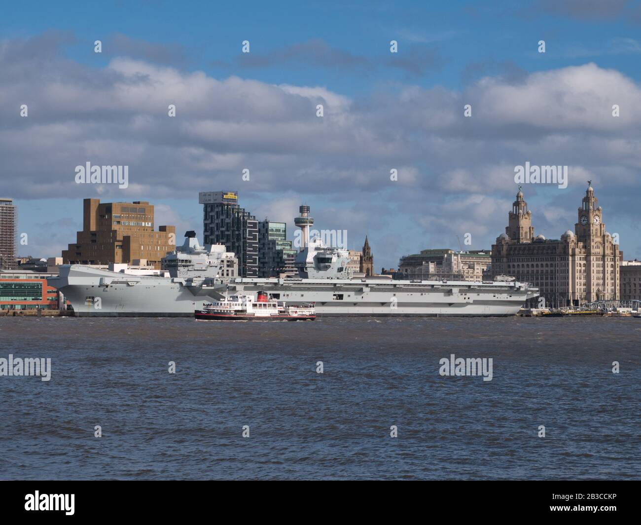 Il Mersey Ferry Royal Iris passa davanti alla compagnia aerea Prince of Wales della Royal Navy, ormeggiata presso il lungomare storico di Liverpool, patrimonio dell'umanità dell'UNESCO, sul Th Foto Stock