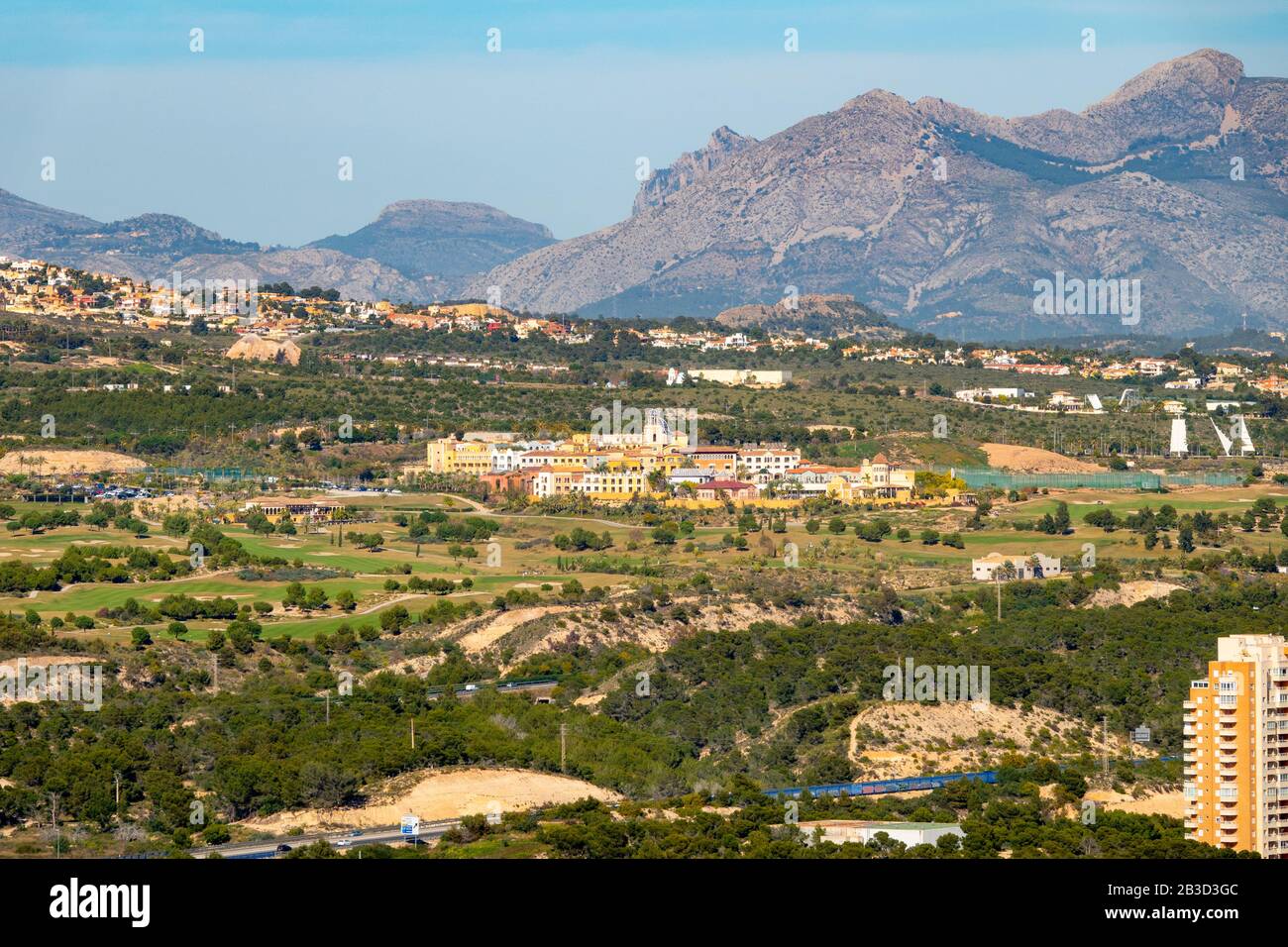 Veduta aerea di lunga distanza del Villaitana Golf Resort a Benidorm, Spagna. Campo da golf e villaggio con sfondo di montagna. Foto Stock