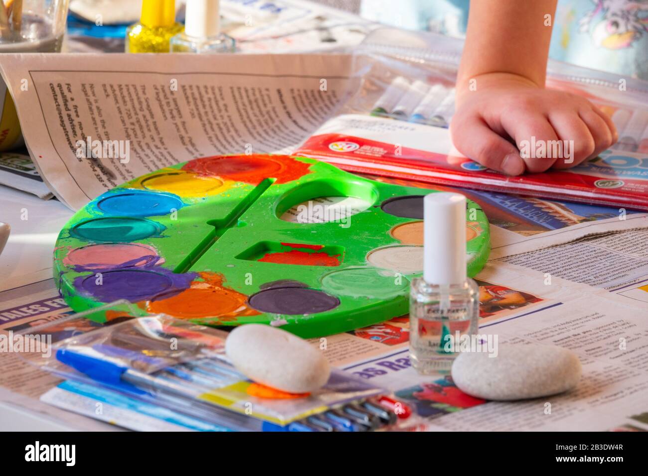 Bambino pittura rocce con acquerelli sul giornale, luminoso con un sacco di colori. Foto Stock