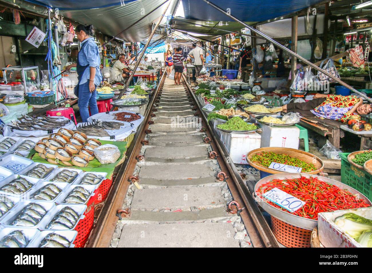 Venditori nel mercato unico Maeklong Wet vendere i loro prodotti e verdure lungo i binari della ferrovia Maeklong Foto Stock