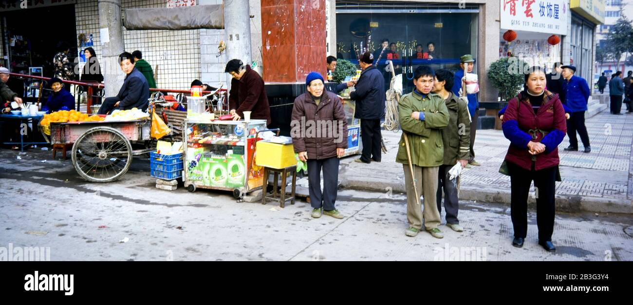 Chongqing China , Marzo 2005 - Persone su una strada trafficata Chongqing, Cina in attesa dell'autobus e mostrando tipici venditori di cibo di strada. Foto Stock