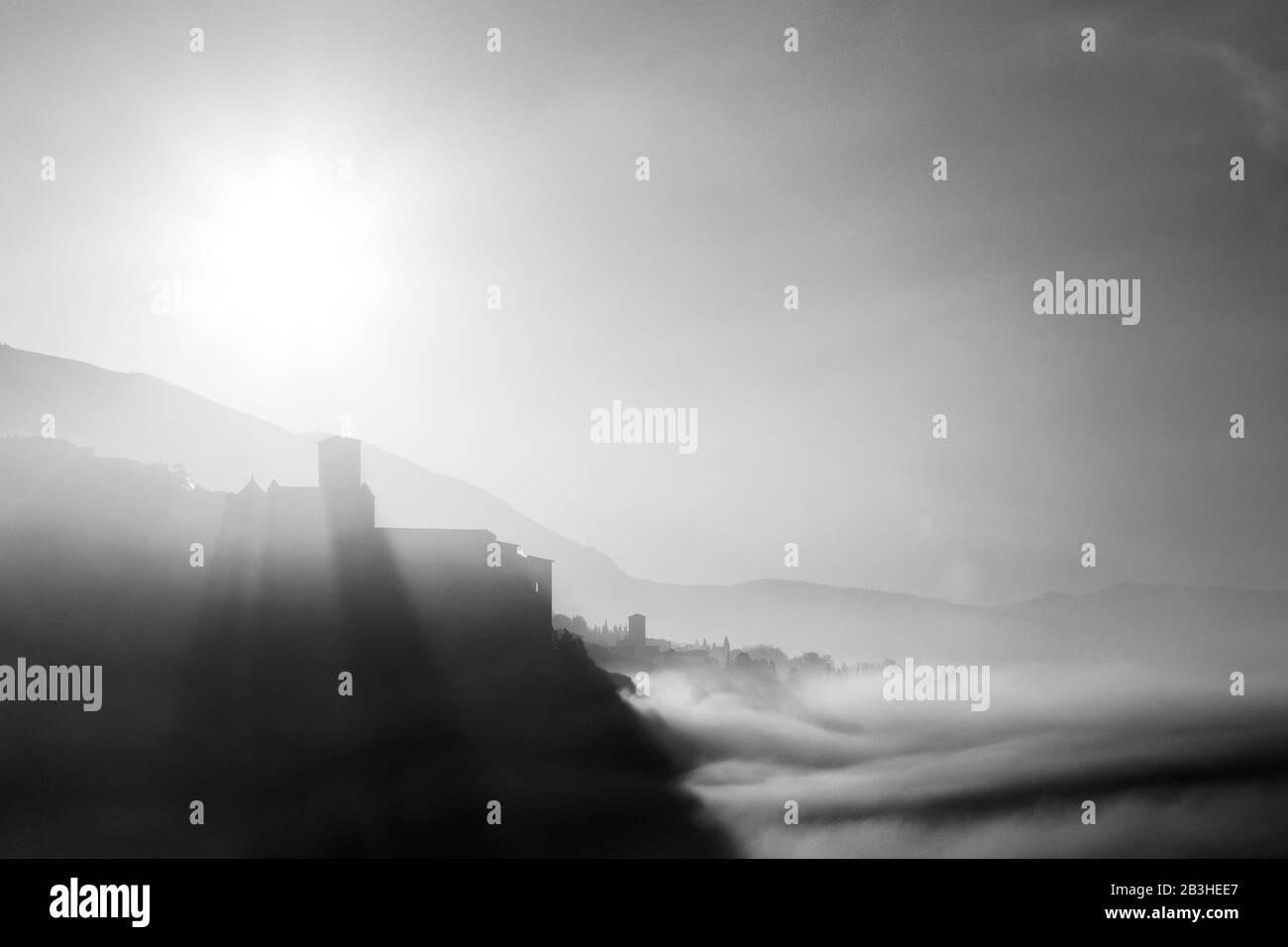 Vista surreale di Assisi e della chiesa di San Francesco (Umbria, Italia) al centro della nebbia all'alba Foto Stock