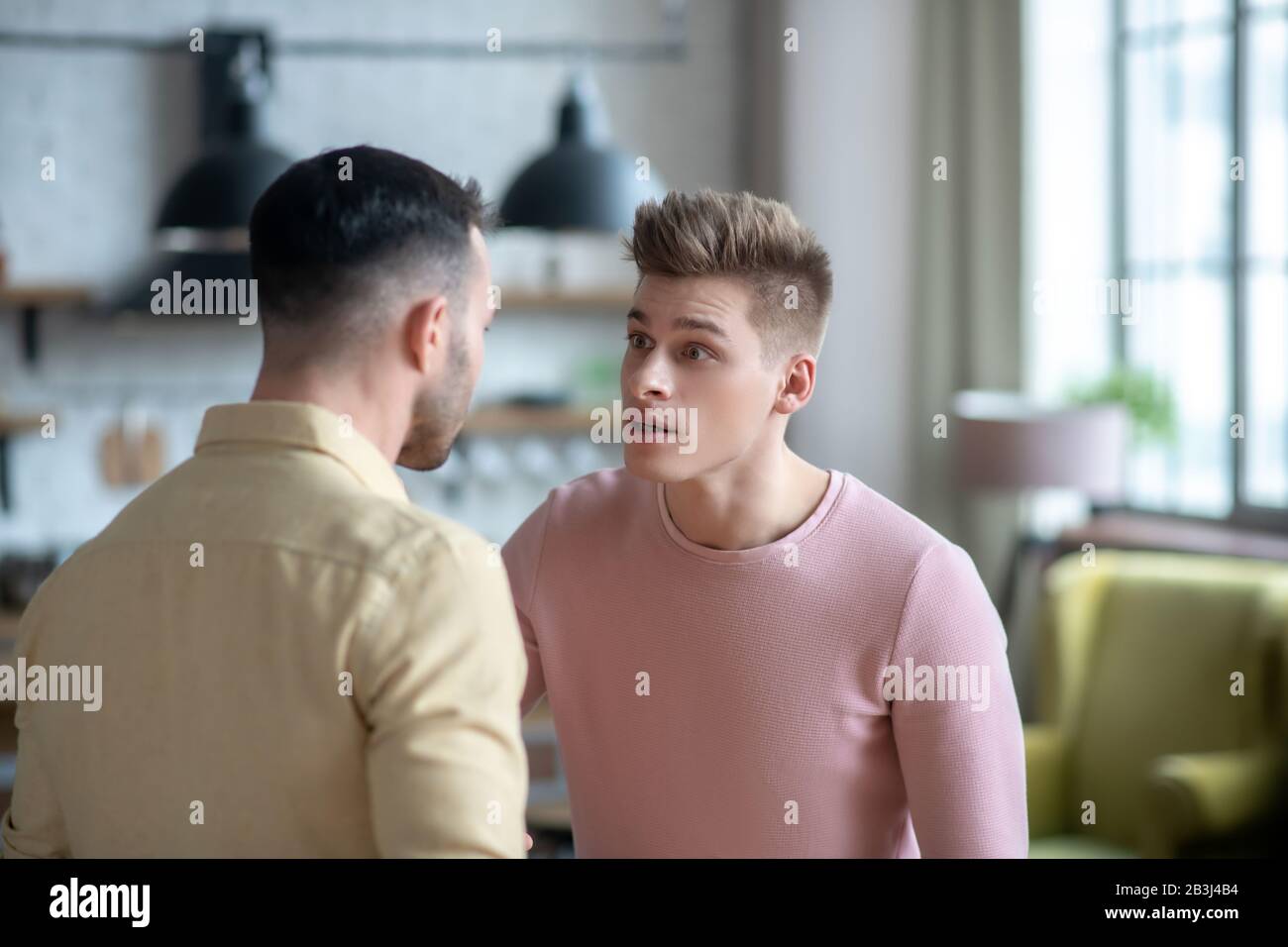Due giovani uomini che hanno un argomento e guardare irrisivo Foto Stock