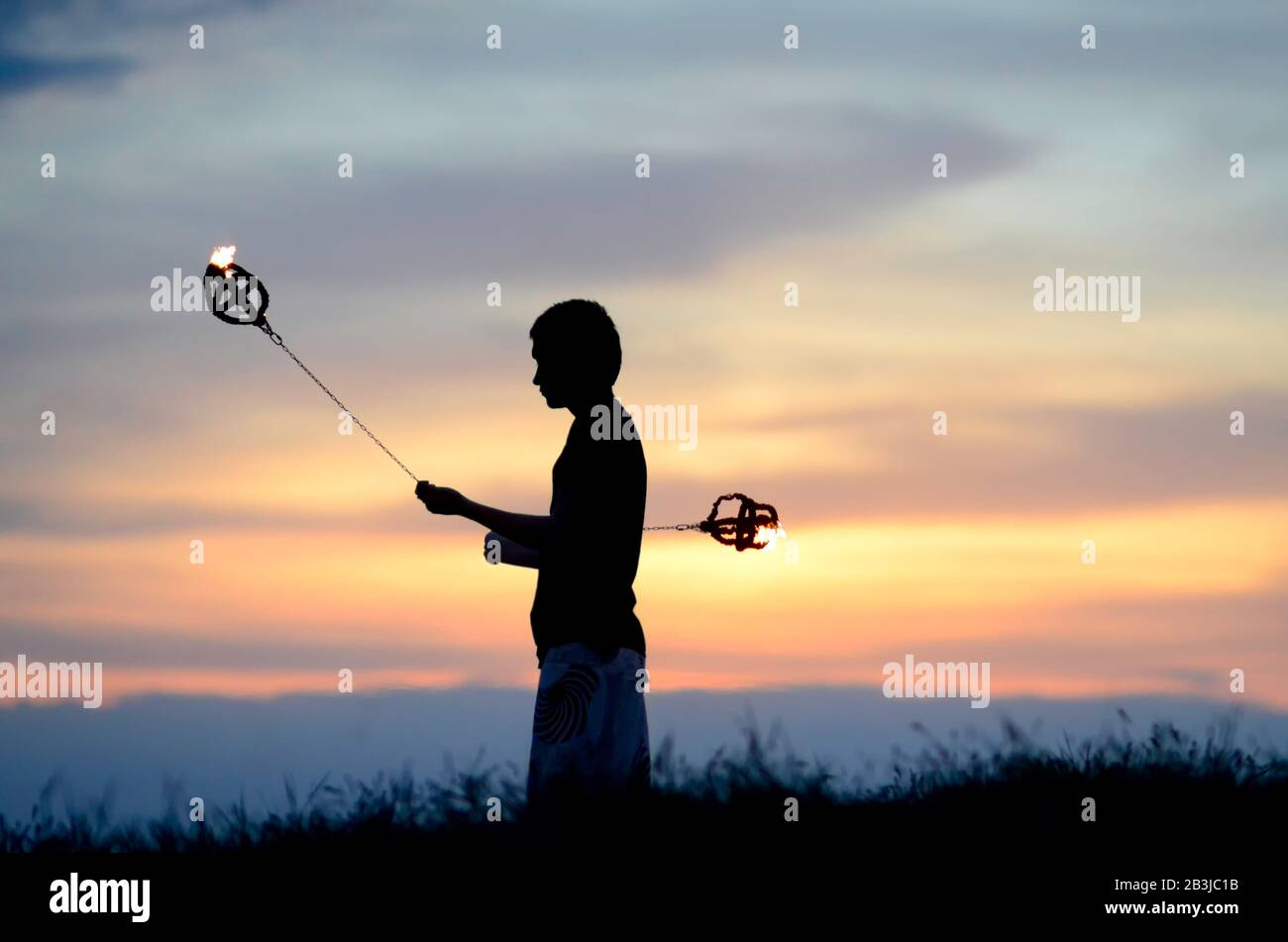 L'artista poi oscilla i pesi infuocati al tramonto Foto Stock