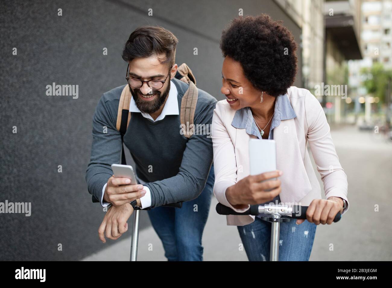 La gente di affari felice che va lavorare con lo scooter elettrico sulla strada urbana Foto Stock