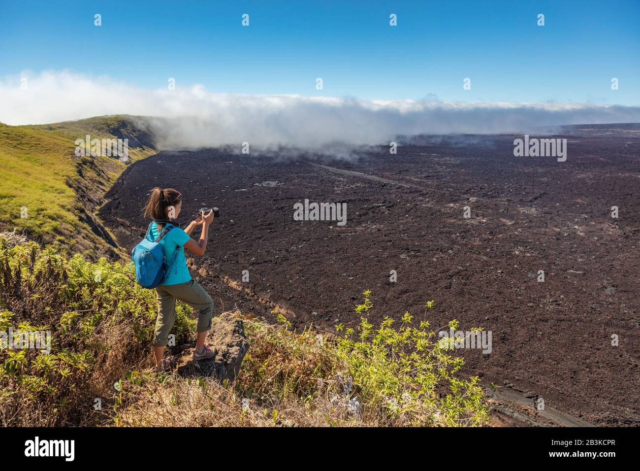 Escursione turistica delle Galapagos sul vulcano Sierra Negra sull'isola di Isabela scattare foto con la macchina fotografica. Donna in escursione sul famoso punto di riferimento, mondi 2nd più grande caldera vulcanica attiva, Galapagos Isole Ecuador. Foto Stock