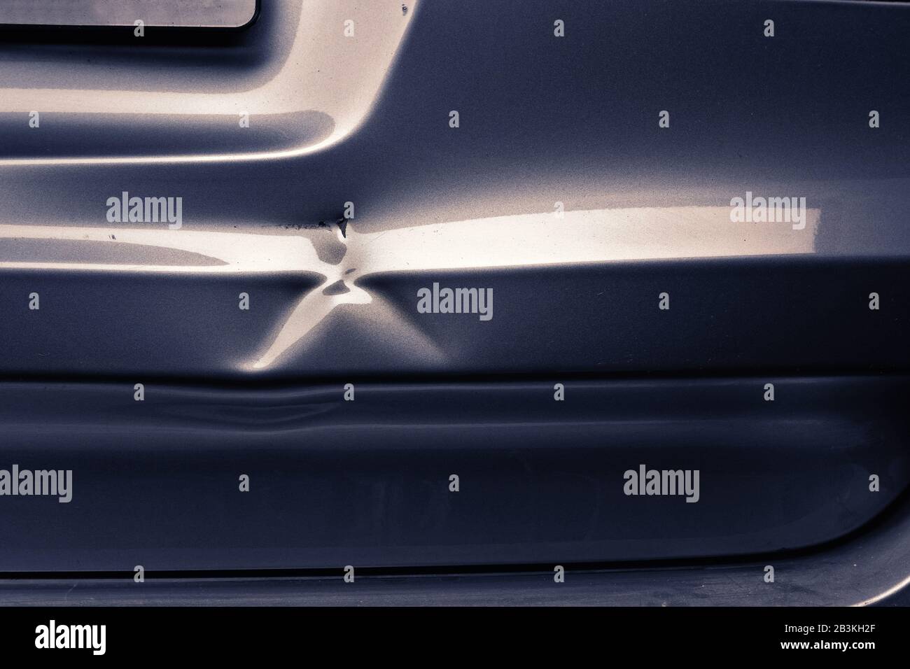 Un'ammaccatura in una piega metallica di un'auto d'argento in luce eccitante. Foto Stock