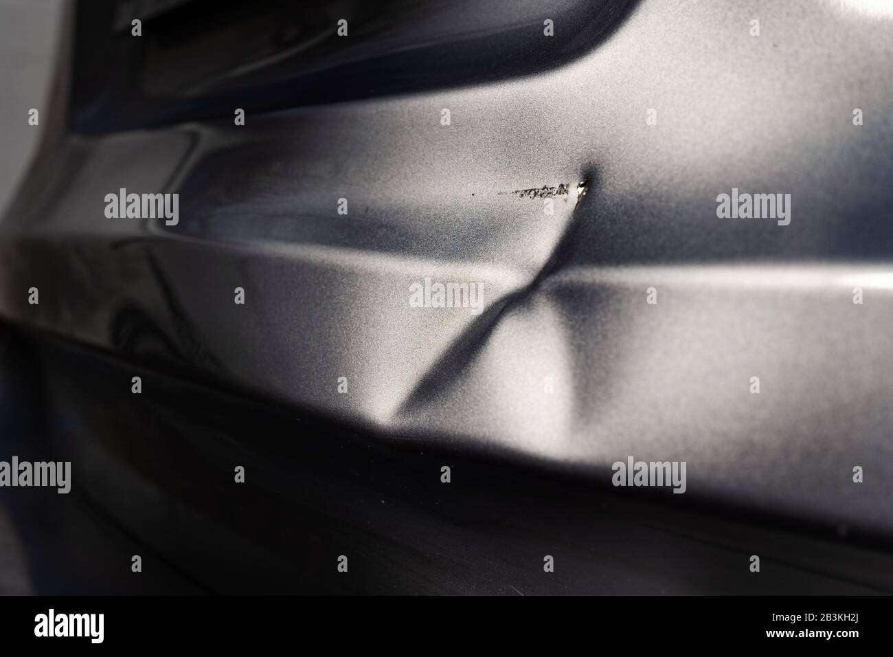 Un'ammaccatura nel corpo di una vettura d'argento in luce eccitante. Foto Stock