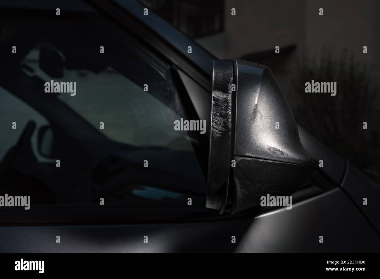 Lo specchietto retrovisore pesantemente graffiato di un'auto color argento. Foto Stock