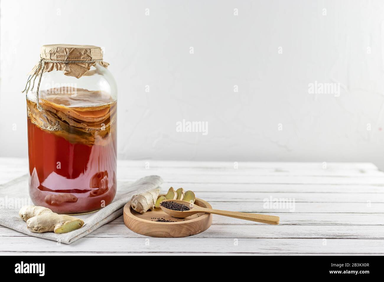 Kombucha superfood pro biotic tè fungo bevanda in bottiglia di vetro e vaso con zenzero, tè su sfondo bianco. Copia spazio Foto Stock