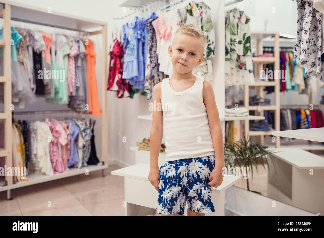 Il ragazzo prova sui vestiti nel negozio di abbigliamento per bambini.  Piccolo uomo di moda che posa in abiti che sceglie Foto stock - Alamy