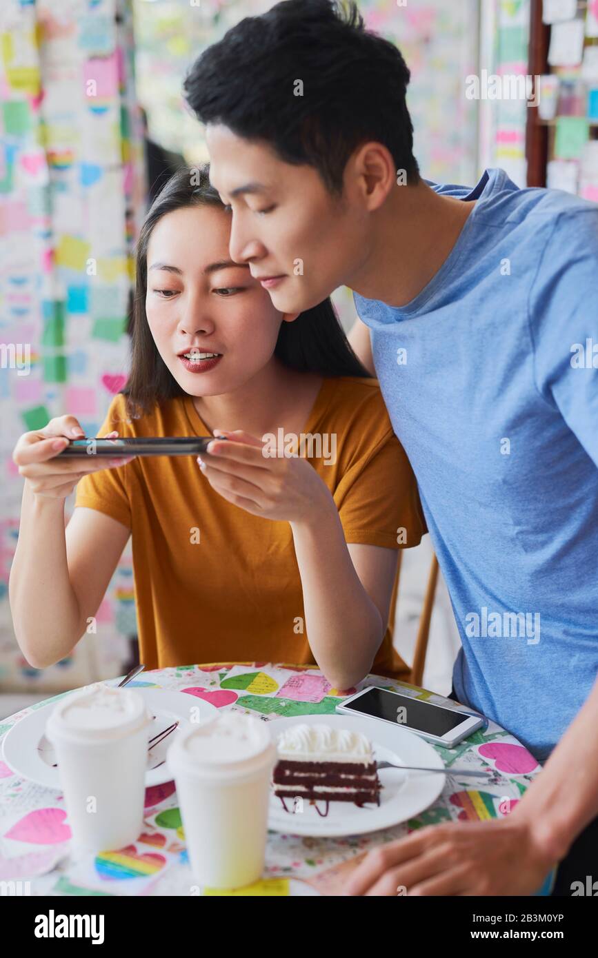 Donna vietnamita fotografando il suo dessert al caffè Foto Stock