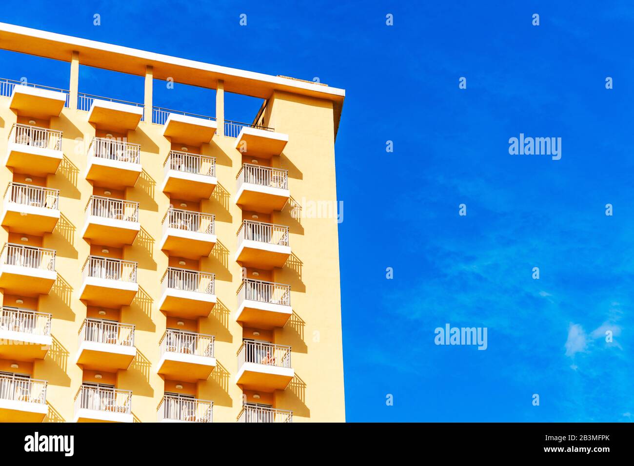 Le camere dell'hotel dispongono di balconi in un edificio moderno. Schema geometrico del balcone sullo sfondo blu del cielo Foto Stock