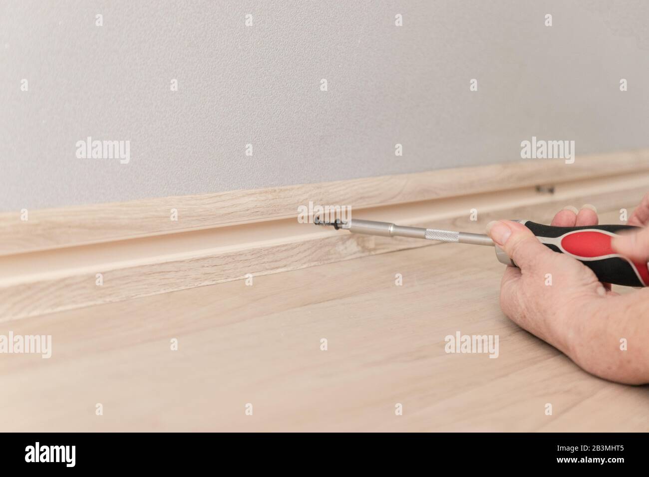 La mano femmina serra la vite con un cacciavite nella parete. Riparazione in casa Foto Stock