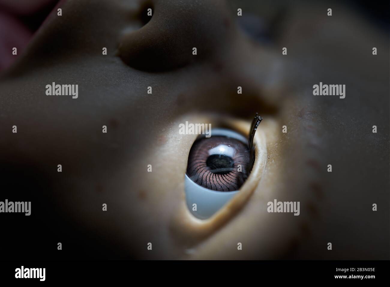 occhio di una vecchia bambola al centro del riflettore, primo piano Foto Stock