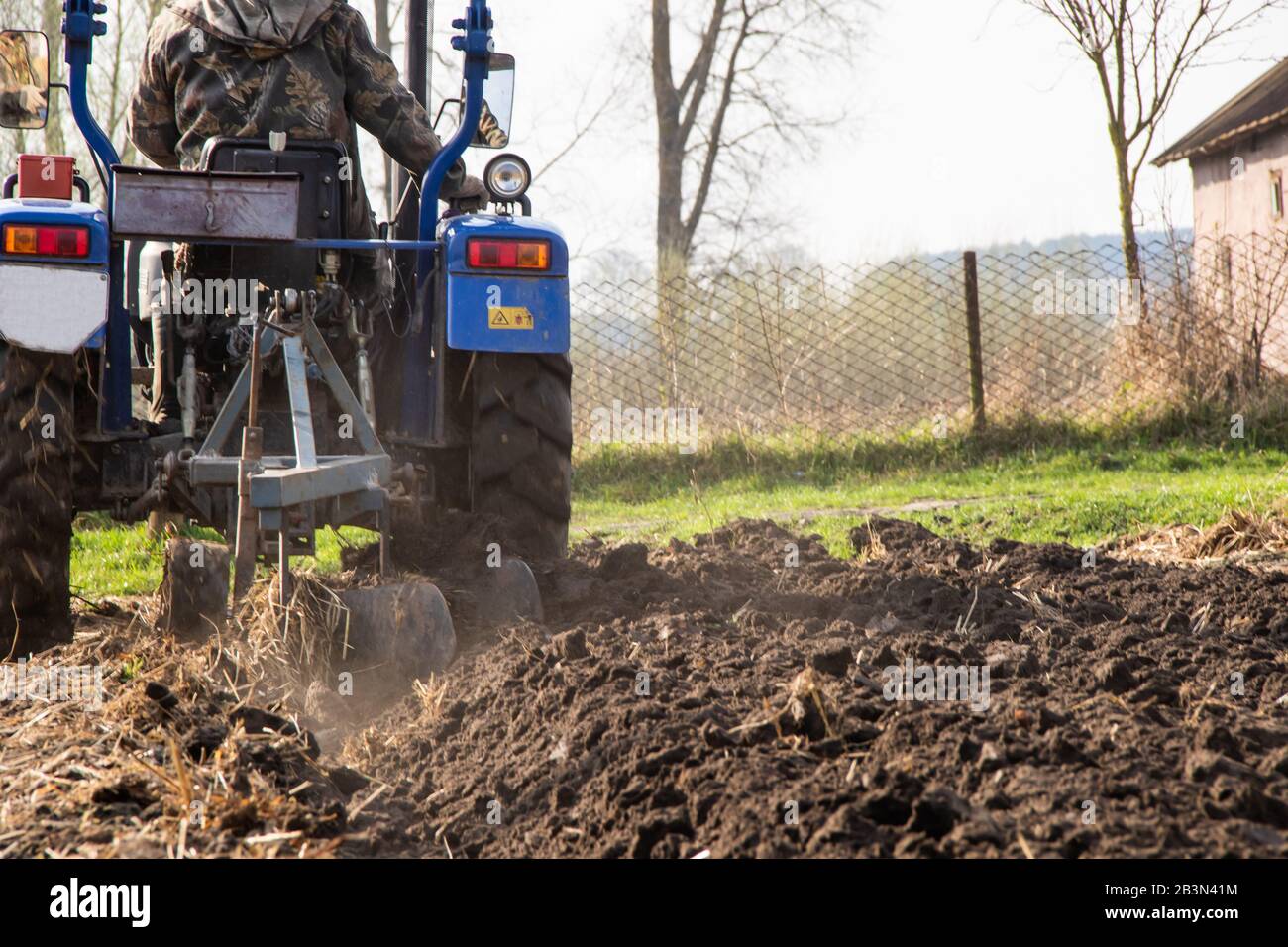 Il trattore arows un campo nella molla accompagnato dai ruscelli preparati per piantare campo agricolo di verdure Foto Stock
