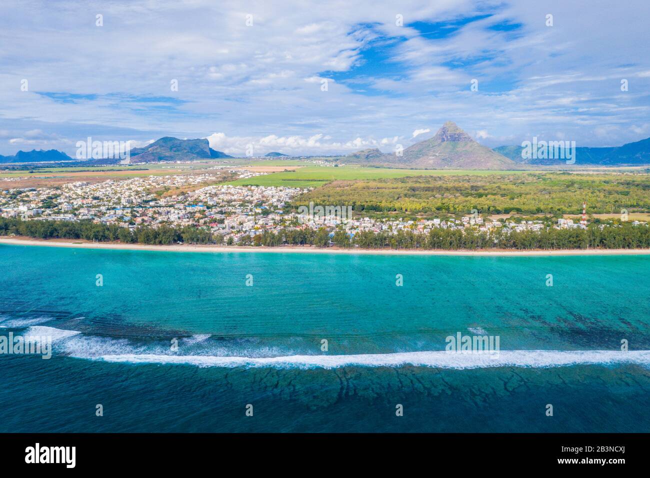 Veduta aerea con il drone delle onde che si infrangono sulla spiaggia di Flic en Flac con Piton de la Petite Riviere Noire, Mauritius, Oceano Indiano, Africa Foto Stock