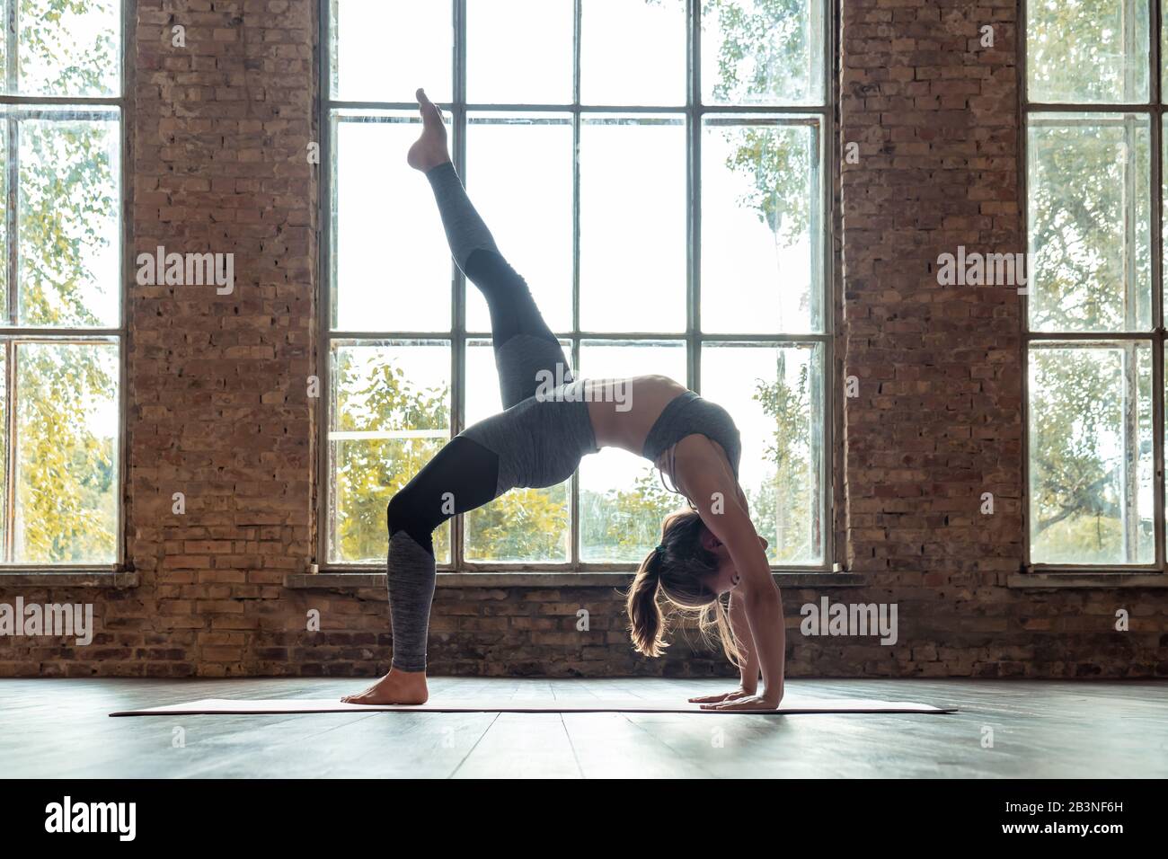 Giovane ragazza sottile pratica hatha yoga una postura del ponte gamba sano stile di vita. Foto Stock